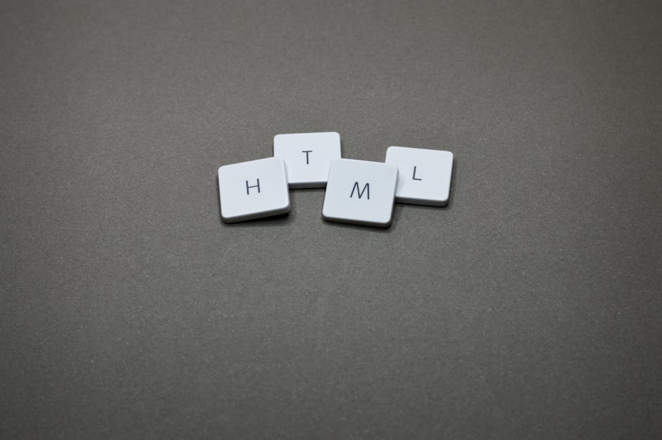 Four white keyboard keycaps arranged on a flat, dark grey surface, each featuring a single black letter spelling out 'H', 'T', 'M', and 'L'. The keycaps are positioned in a loose cluster with slight o